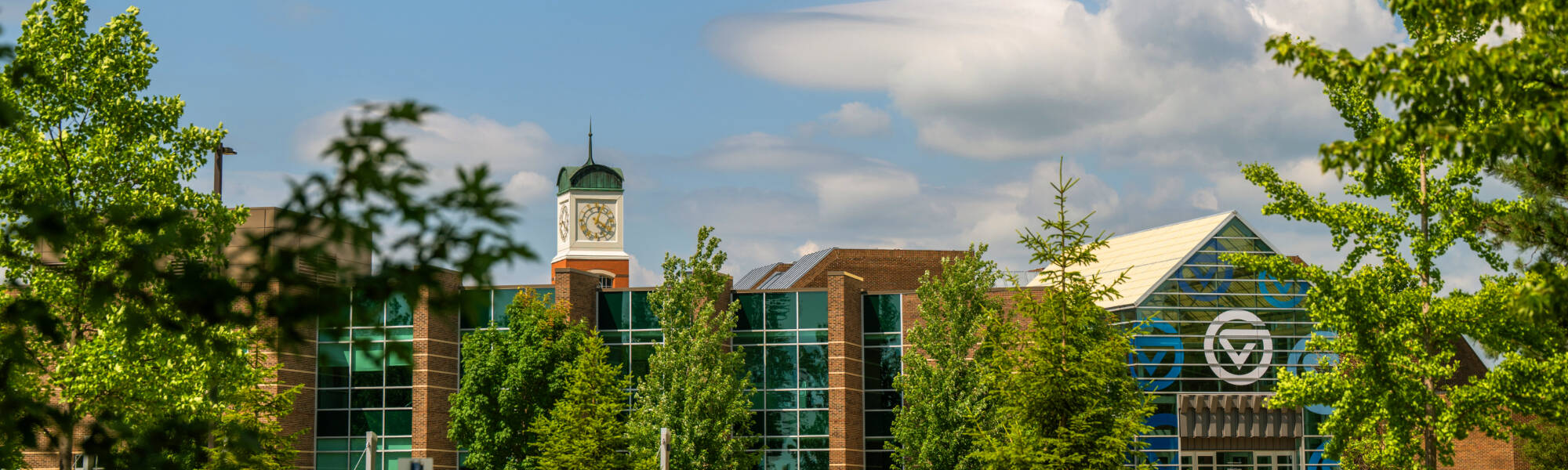 View of the clocktower and Kirkhof Center in between green trees